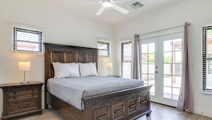 A bedroom with a wooden bed, two bedside tables, a ceiling fan, and a sliding glass door. - PHX Group Retreat By Dtwn! New Build w/ Patio (Phoenix)