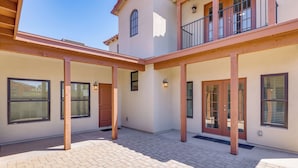 A spacious courtyard with a covered patio area, large windows, and a two-story building with a balcony. - PHX Group Retreat By Dtwn! New Build w/ Patio (Phoenix)