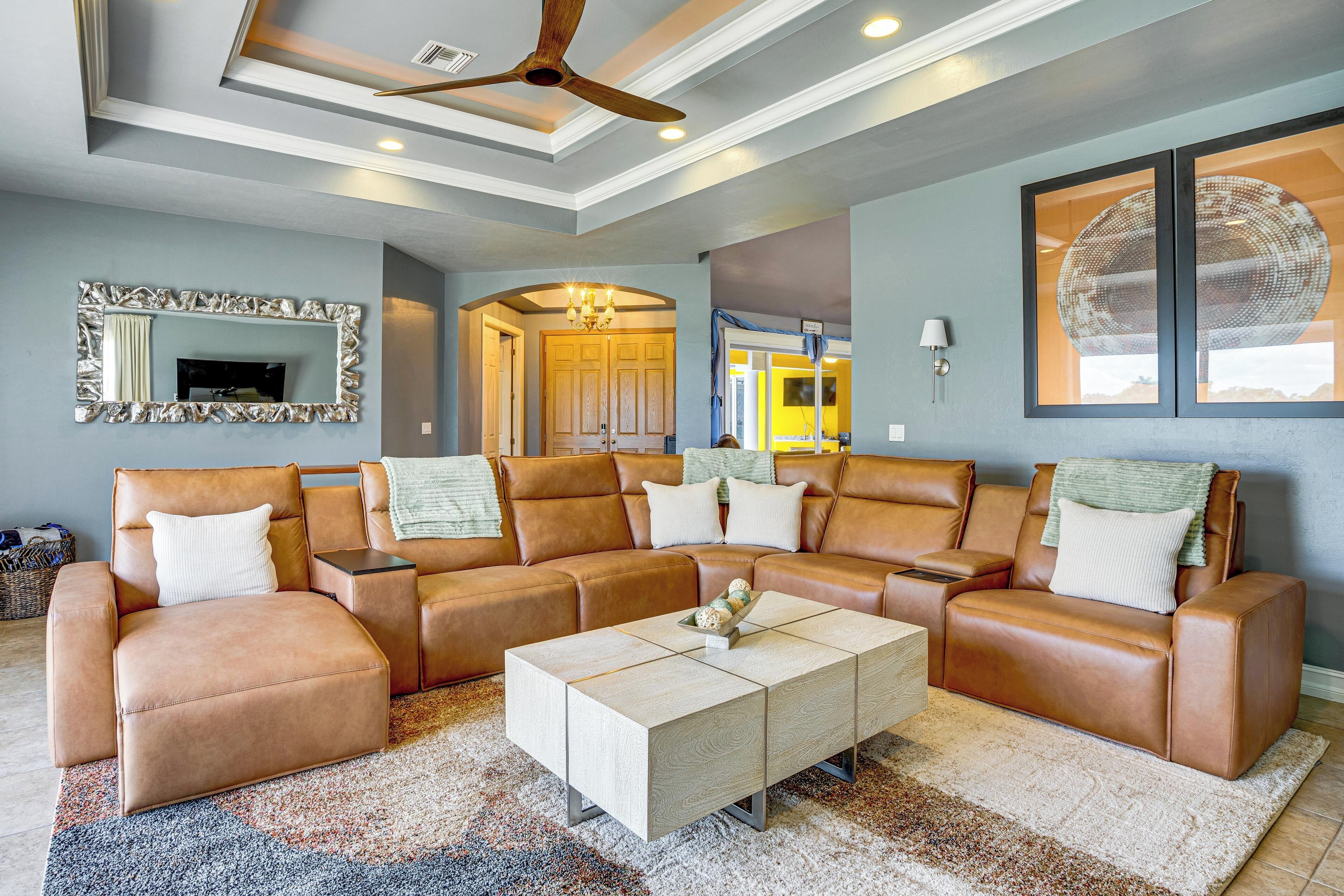Un salon spacieux avec un canapé d’angle, une table basse et un ventilateur de plafond.