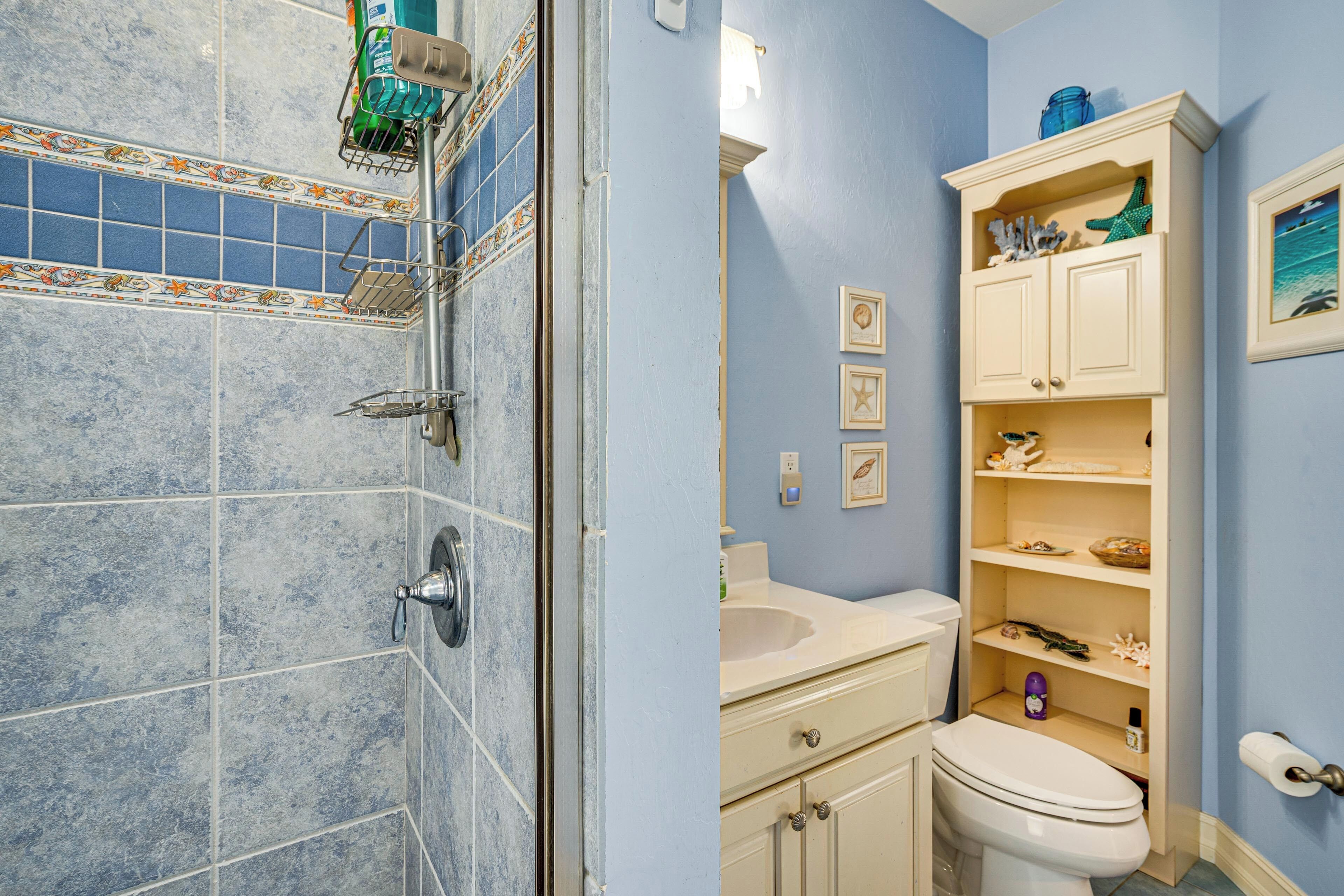 A bathroom with a shower, toilet, sink, and shelves with toiletries.