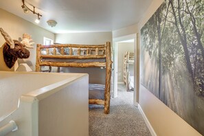 Una cama litera con diseño rústico, una decoración de cabeza de alce montada en la pared y un mural con temática de bosque.