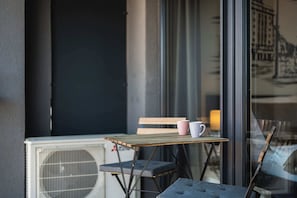 Ein kleiner Außenbereich mit Tisch und Stühlen, einer Bank und einem Fenster mit Blick auf Gebäude.