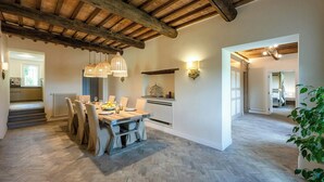 Un comedor amplio con una mesa y sillas de madera, una cocina al fondo y un piso con patrón de espiga.