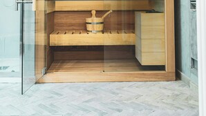 Una sauna con interior de madera, puerta de vidrio y un banco.