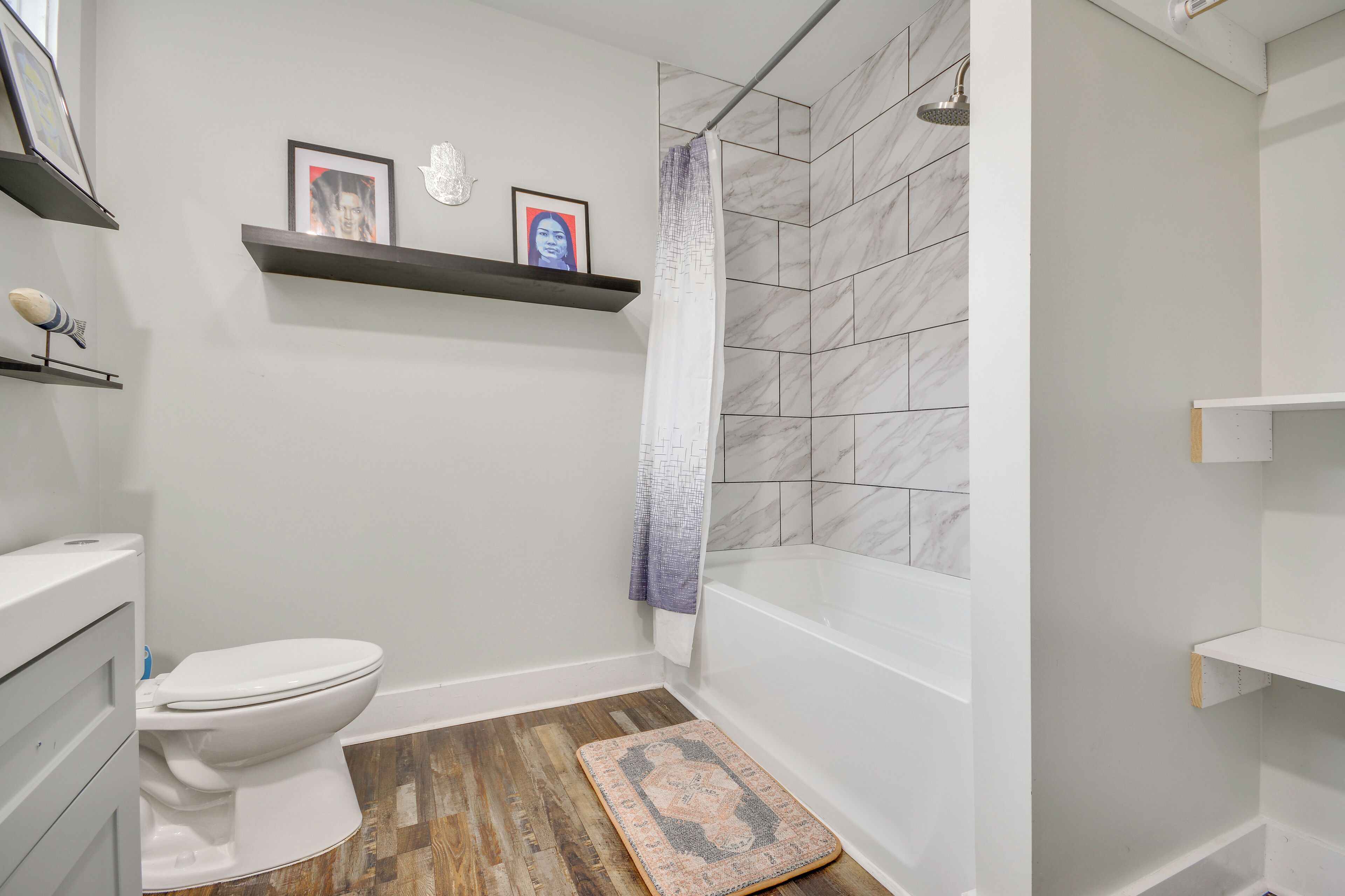 Une salle de bain avec des toilettes, une douche et un tapis de sol en bois.