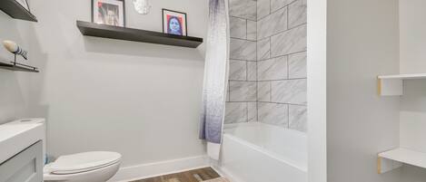 Une salle de bain avec des toilettes, une douche et un tapis de sol en bois.