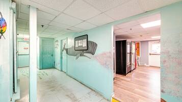 Un pasillo con pared verde azulado, un mural y una puerta señalizada con “EXIT”.