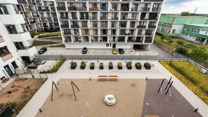 Un immeuble résidentiel à plusieurs étages, doté de balcons, d’une aire de jeux et d’un espace de stationnement.