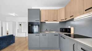 Une cuisine moderne avec des meubles gris, un four noir et un micro-ondes.