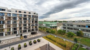 Un immeuble à plusieurs étages doté de balcons, d’un espace de stationnement et d’un espace vert agrémenté de jardinières.
