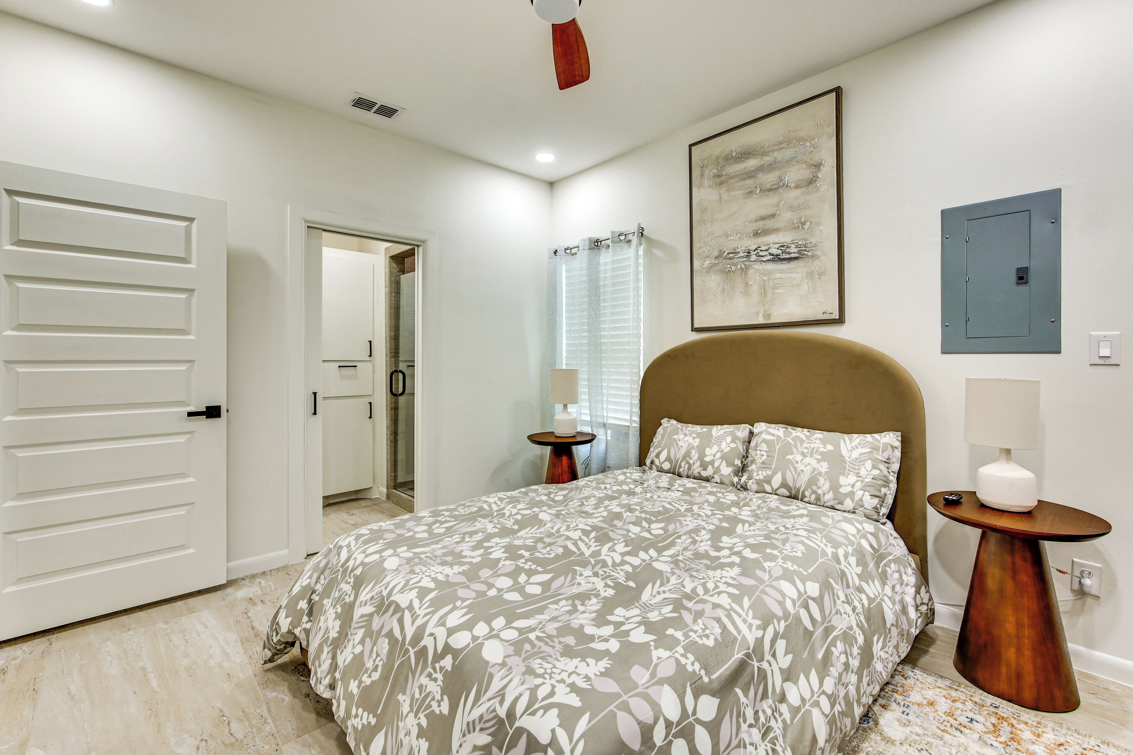 Ein Schlafzimmer mit einem Bett, einer Tür, einem Badezimmer und einer wandmontierten Lampe.