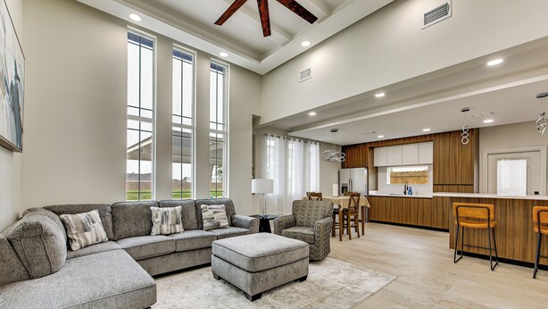A spacious living area with a sectional sofa, ottoman, and a bar area with stools. - Modern Getaway w/ Private Patio & Grill in Mcallen (McAllen)