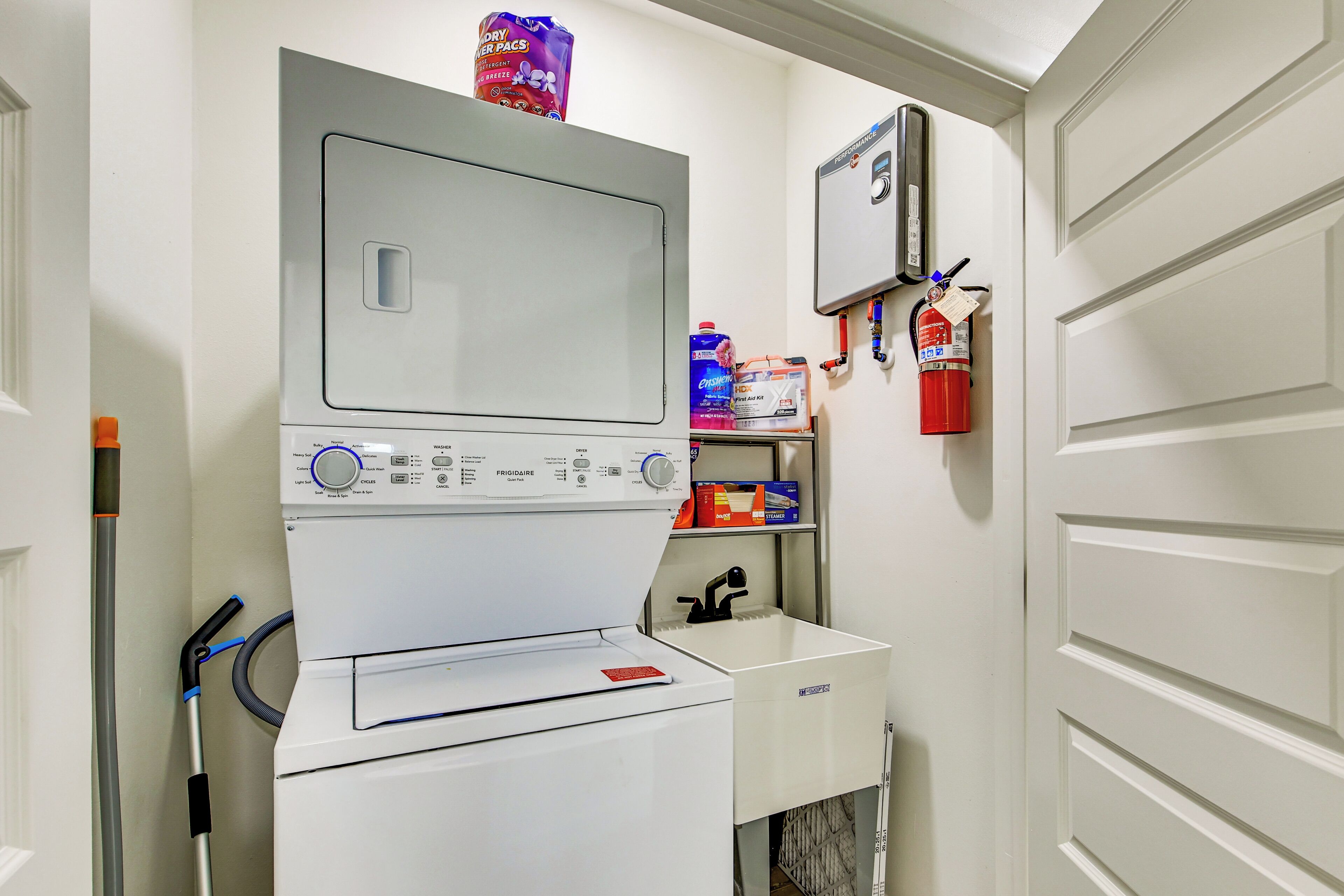 Een wasruimte met een wasmachine, een droger en een brandblusser aan de muur.