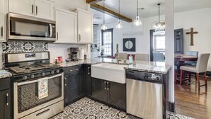 Una cocina equipada con microondas, estufa y lavaplatos. Hay una zona de comedor con sillas y una mesa.