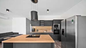 Una cocina moderna con una isla central, electrodomésticos integrados y una paleta de colores oscuros.