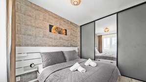 Un dormitorio moderno con una cama grande, cabecera de madera, mesita de noche y espejo.
