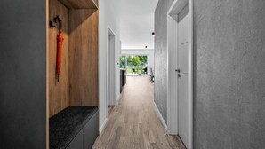 Un pasillo con un banco de madera, una puerta y vistas a un espacio exterior.