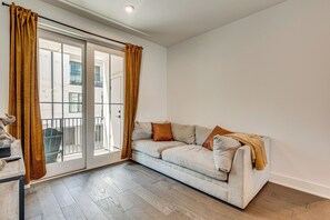 A living room with a sofa, a table, and a view through a sliding glass door.