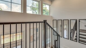 A staircase with a black railing, large windows, and a view of the outdoors. - 1 Mi Decatur Square New Condo Walkable to Marta (Decatur)