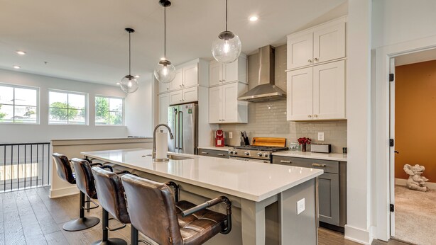 A modern kitchen with a large island, bar stools, pendant lighting, and a view of the outdoors. - 1 Mi Decatur Square New Condo Walkable to Marta (Decatur)