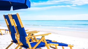 Una spiaggia con lettini di legno e un ombrellone blu.