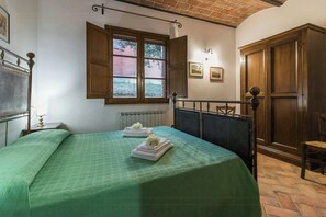 A room with a bed, a window, a radiator, and a wooden wardrobe. - Apartment near Lake Trasimeno with view (Castiglione del Lago)