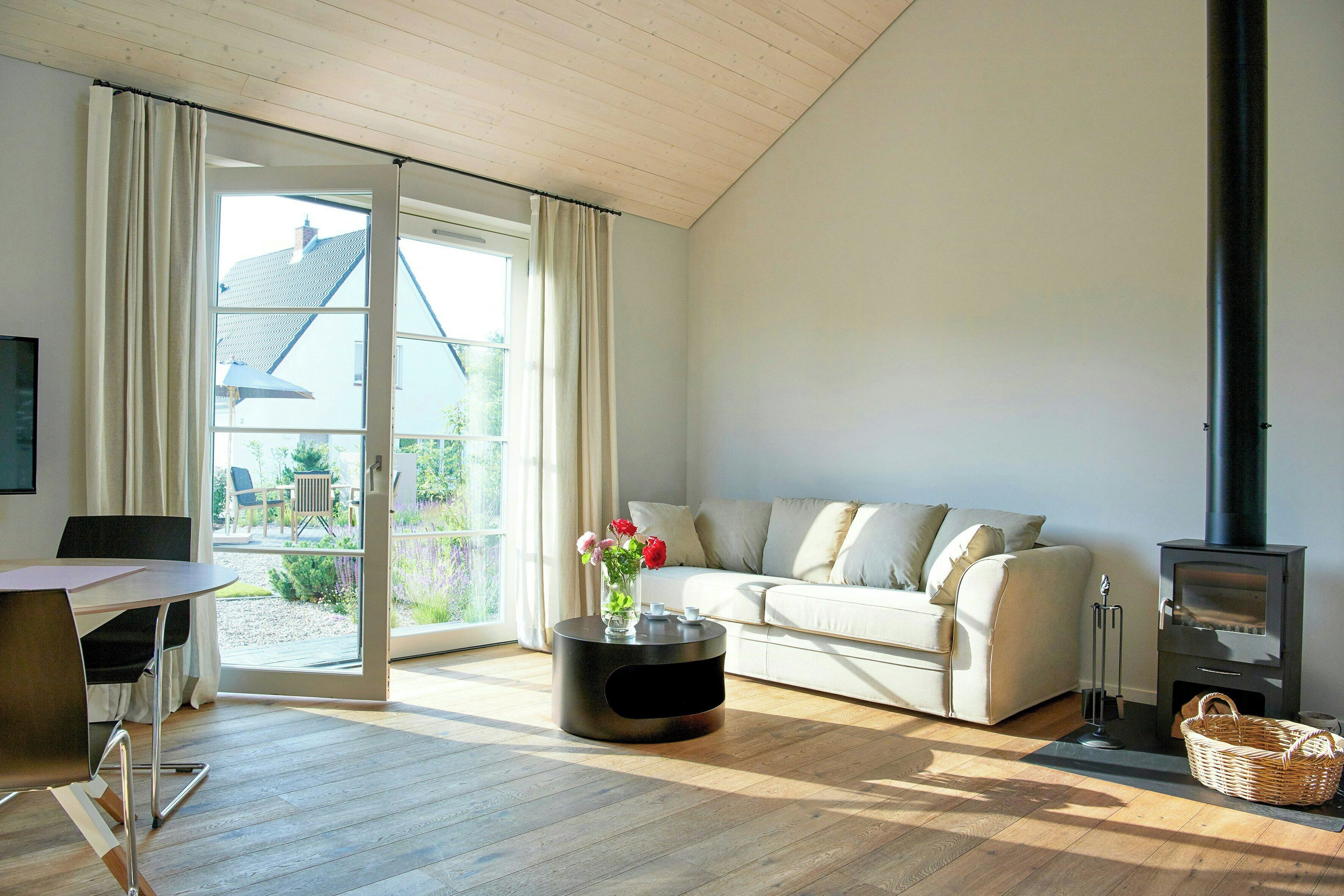 Ein modernes Wohnzimmer mit einer Couch, einem runden Couchtisch, einem Kamin und einem Essbereich mit Tisch und Stühlen.