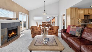 Ein Wohnzimmer mit Kamin, Ledersofa und Essbereich mit Stühlen und Tisch.