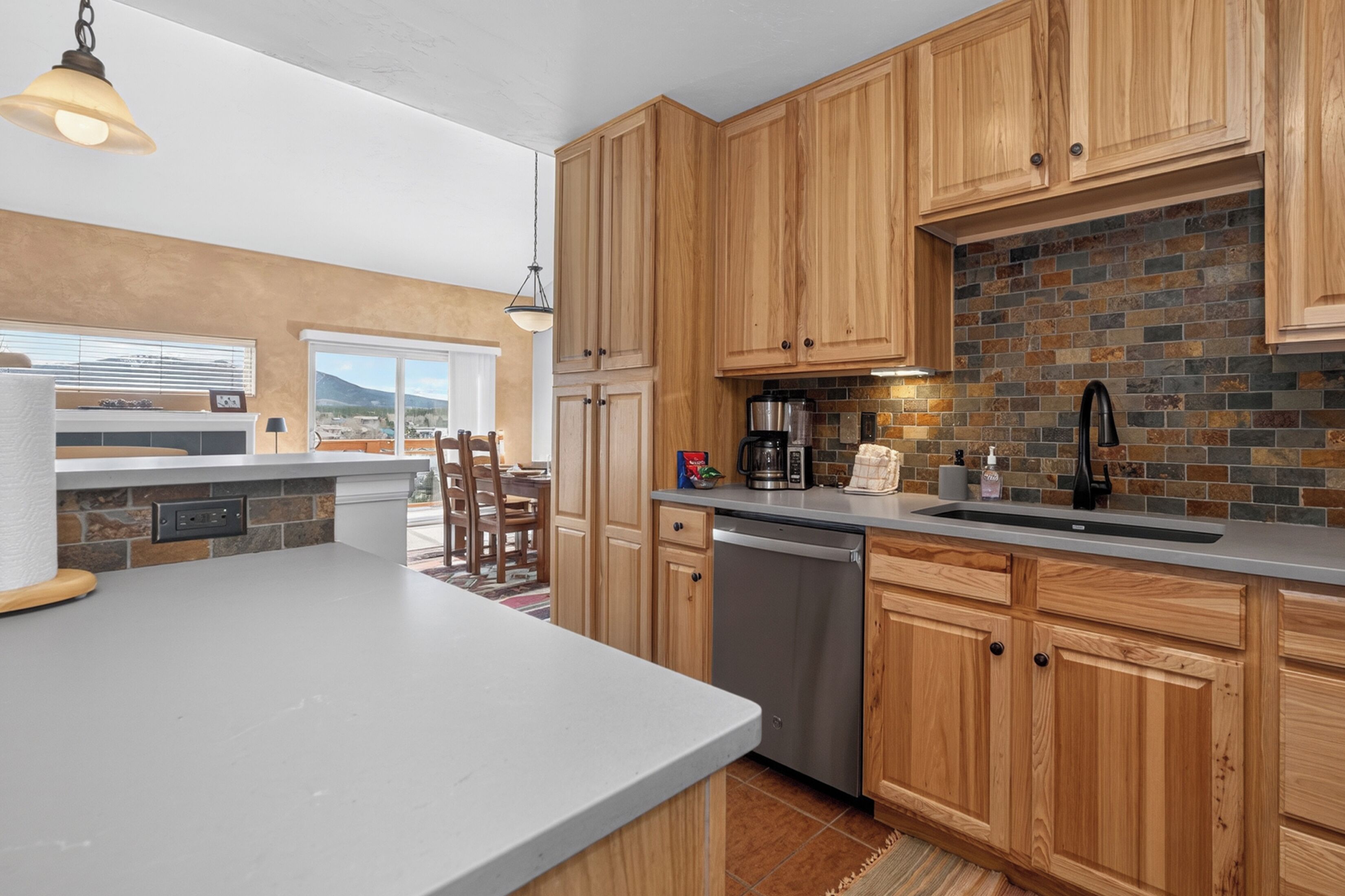 Eine moderne Küche mit Holzschränken, einer Backstein-Spritzschutzwand und einem Geschirrspüler.