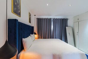 A bedroom with a bed, a headboard, curtains, a wardrobe, and a lamp. - Boutique Hotel-Style Room In Ferndale-E5 (Randburg)