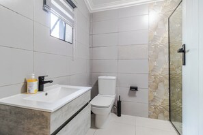 A bathroom with a white sink, a toilet, and a shower area. - Boutique Hotel-Style Room In Ferndale-E5 (Randburg)