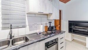 Cozinha moderna com forno embutido, pia e bancada com cafeteira.