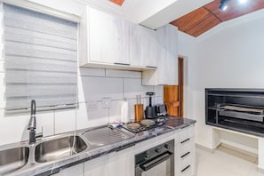 Una cocina moderna con horno empotrado, un fregadero y una encimera con cafetera.