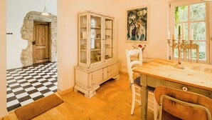 A room with a checkered floor, a wooden door, a cabinet with glass doors, a dining table with chairs, and a window with a view of greenery. - Experience original nature in the steward's house (Kall)