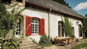 A rustic stone building with red shutters, a wooden table, and chairs outside. - Experience original nature in the steward's house (Kall)