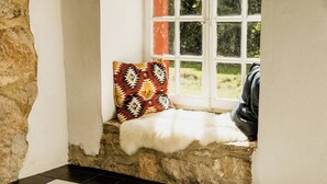 A stone wall, a checkered floor, a window with a view, and a white furry rug. - Experience original nature in the steward's house (Kall)