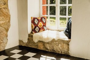 A stone wall, a checkered floor, a window with a view, and a white furry rug. - Experience original nature in the steward's house (Kall)