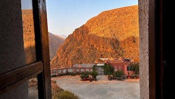 A view through an arched doorway of a building with a parking lot and a mountainous landscape in the background.