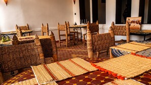 Una habitación con muebles y alfombras de fibras naturales, un comedor con mesas y sillas, y vistas al exterior a través de ventanas.