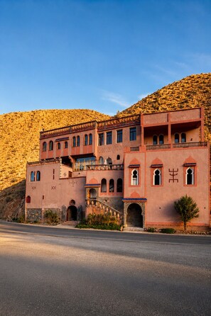 A large, multi-story building with a traditional architectural style, featuring arched windows and a balcony. - Riad Bleu Afriqua (Ait Sedrate Jbel El Soufla)