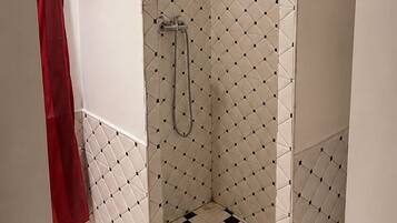 A bathroom with a shower area, white tiled walls, and a black and white checkered floor.