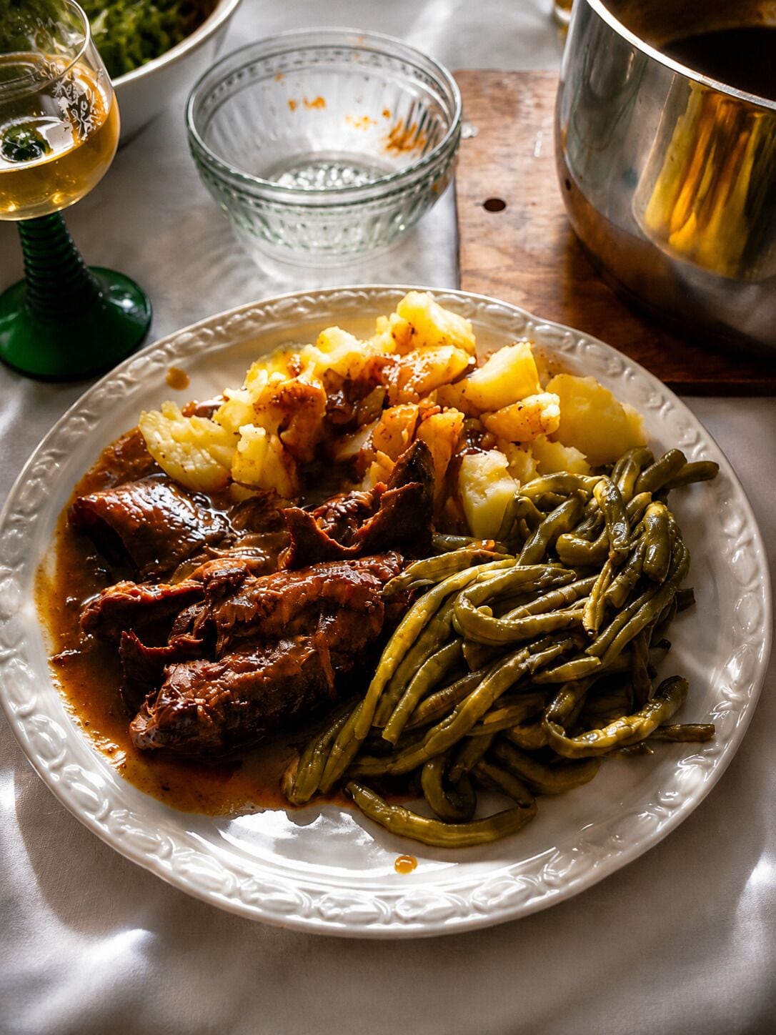 A plate with a meal consisting of meat, potatoes, and green beans.