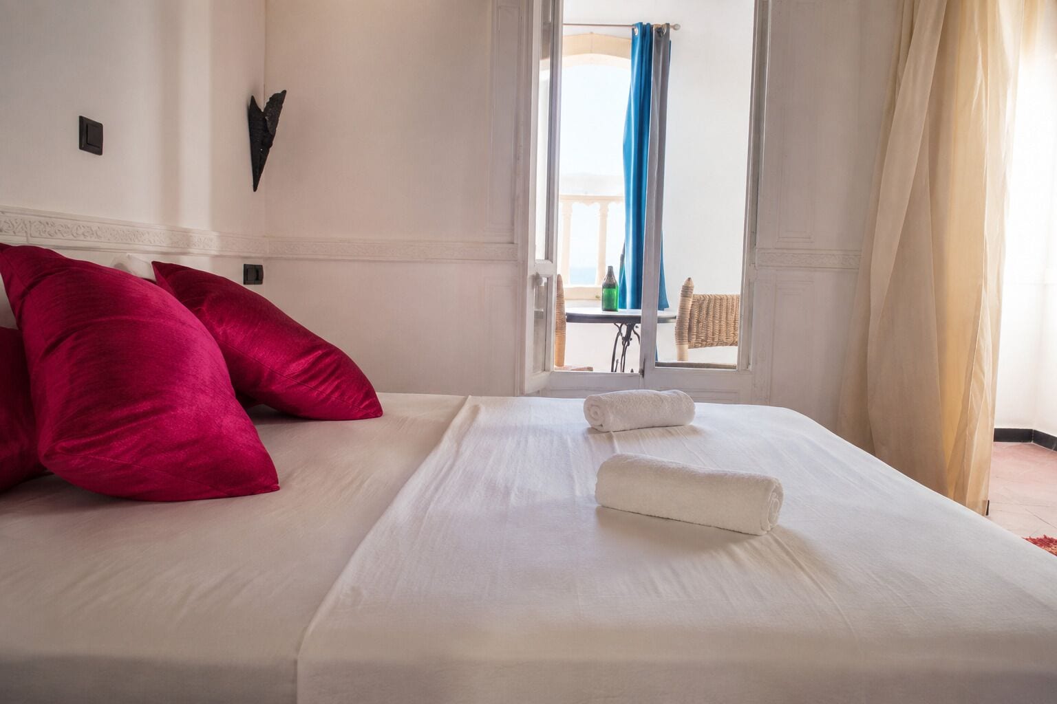 A hotel room with a bed, pillows, and a view of the outside.
