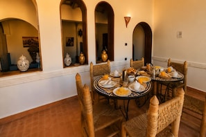 A dining area with a round table set for breakfast, featuring a variety of dishes and drinks.
