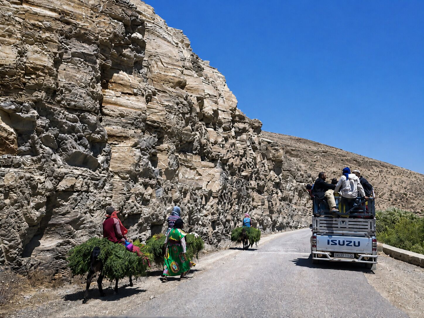 Un paisaje rocoso con una carretera y un vehículo transportando personas y mercancías.