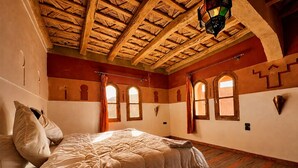 Una habitación con techo de madera, cama con cubrecama acolchado y alfombra estampada.