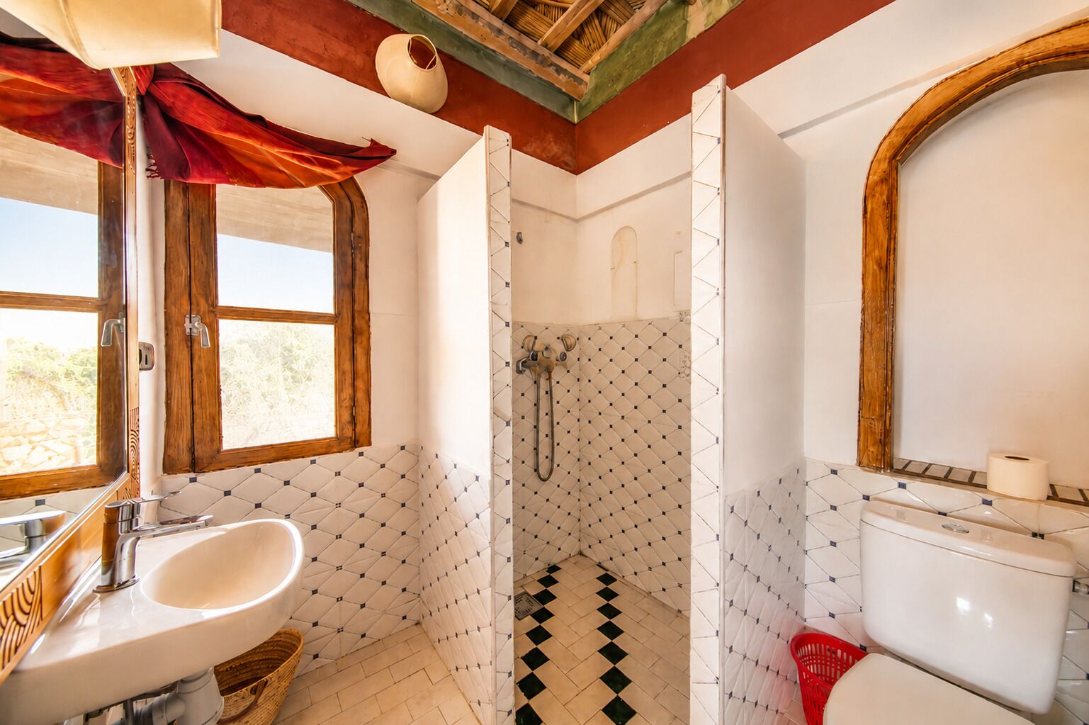 A bathroom with a sink, toilet, shower, and a window.