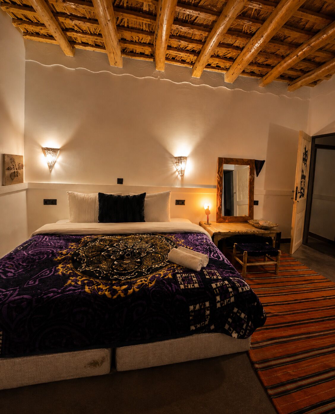 Quarto de hotel com cama, abajures, teto de madeira e espelho.