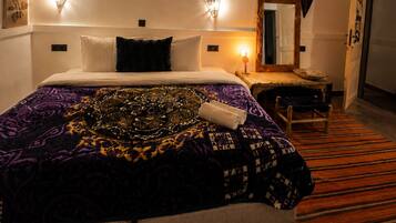 Quarto de hotel com cama, abajures, teto de madeira e espelho.