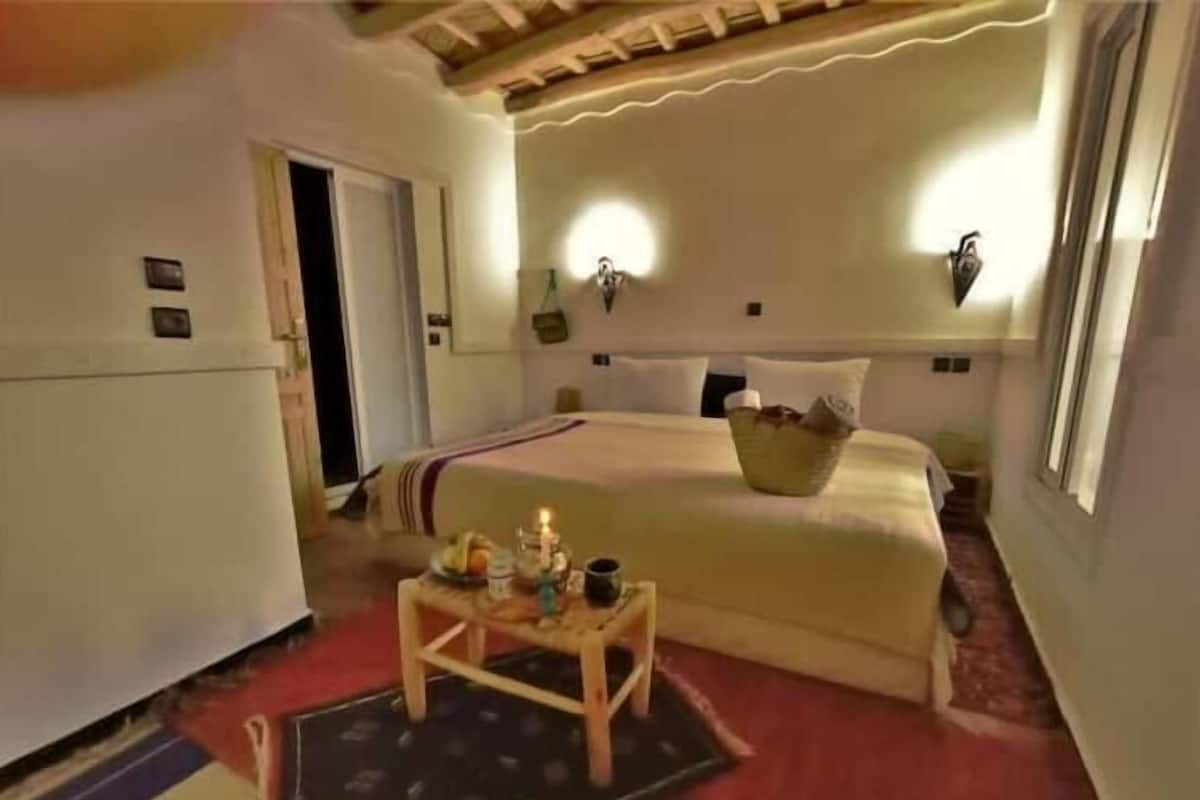 Un dormitorio con cama, mesita de noche y lámpara de pared.